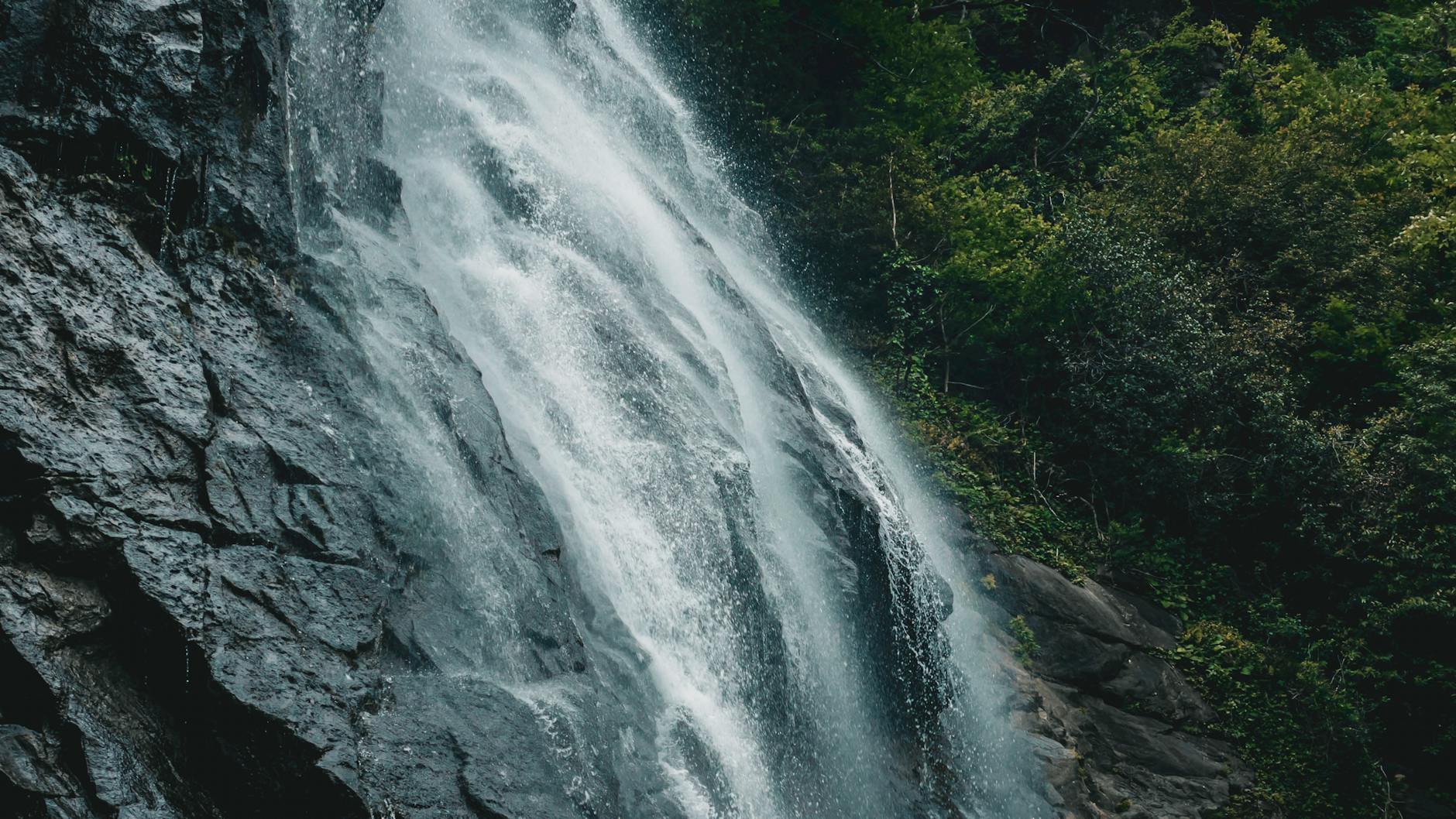 Captivating view of a powerful waterfall cascading amidst lush greenery in Artvin, Türkiye.