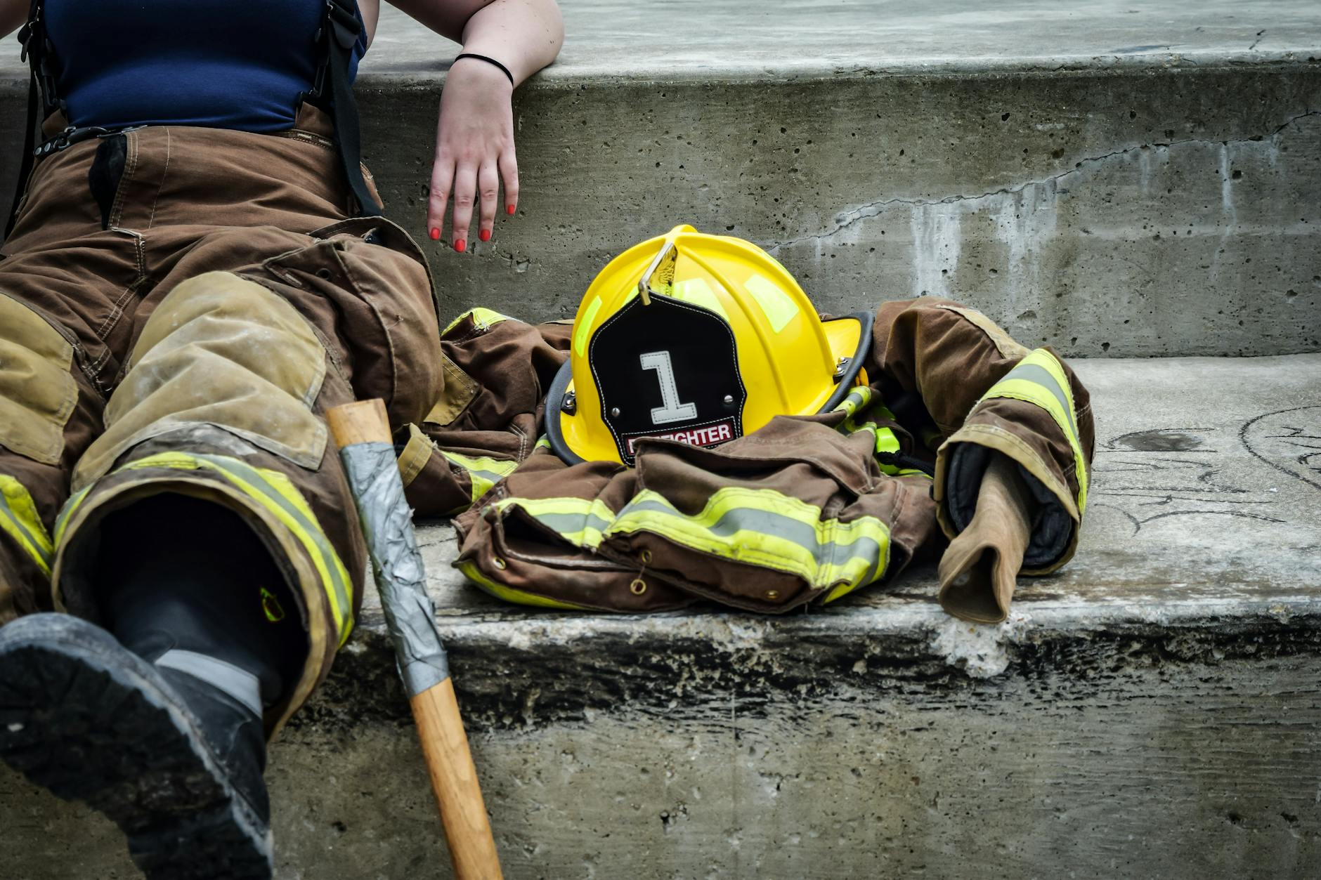 Toxic Mushroom Alert: Discover Causes, Symptoms, and Essential Steps Firewoman taking a break on concrete steps with gear and helmet nearby.