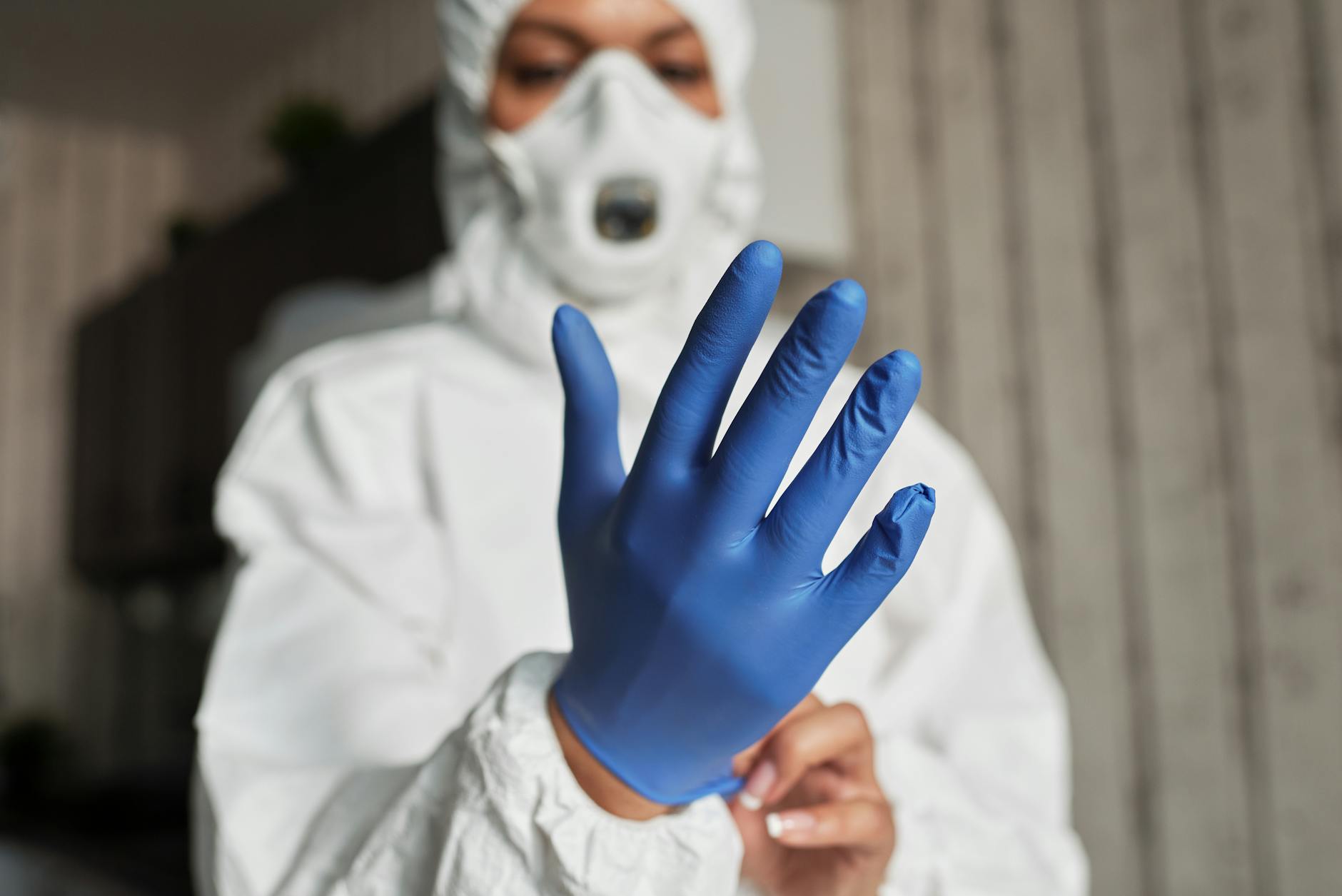 Close-up of a healthcare worker putting on blue latex gloves for protection.