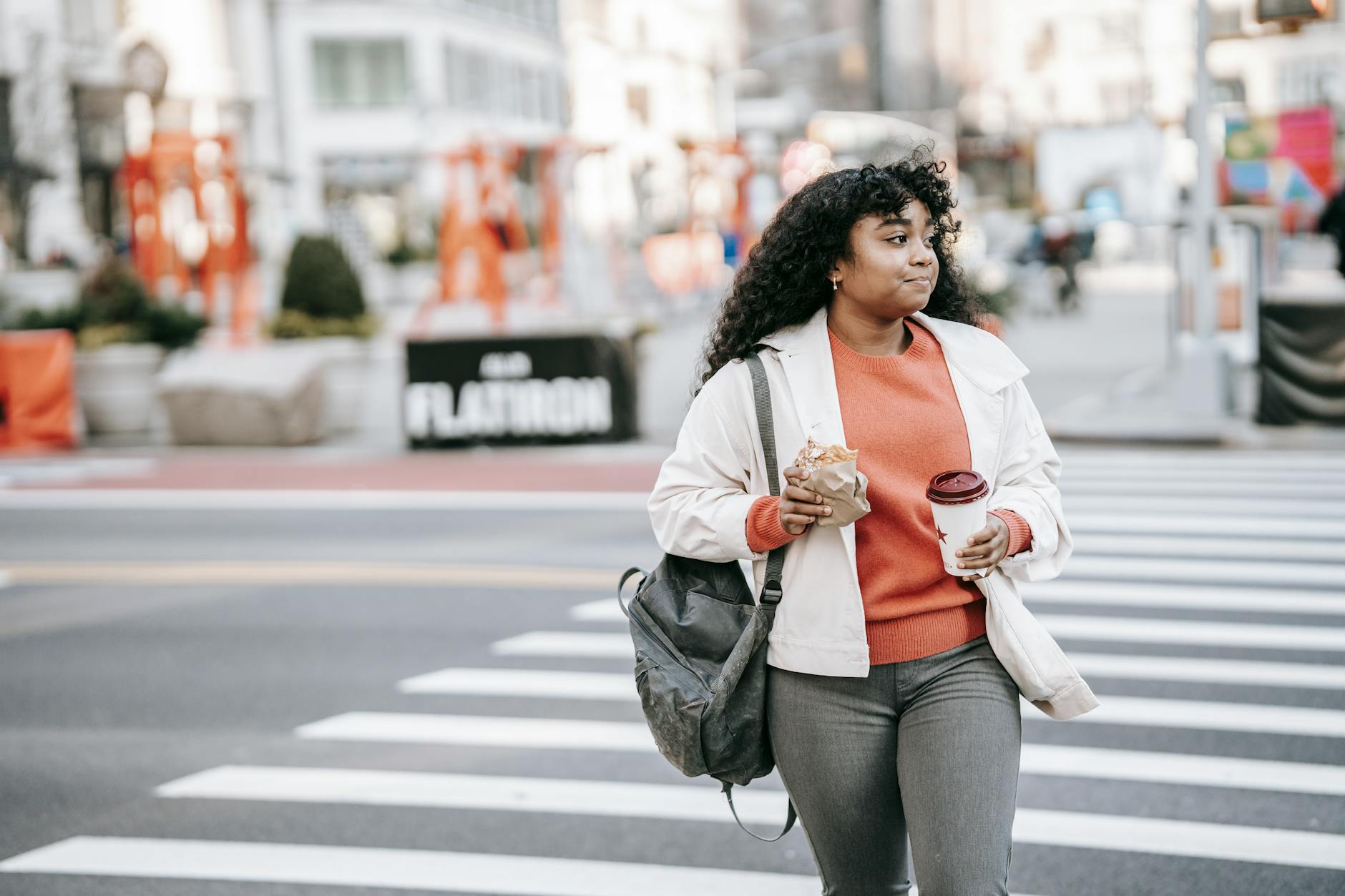 Urban Mushroom Foraging: Best Spots for Effortless Edible Finds African American woman crossing city street with coffee and sandwich in hand.